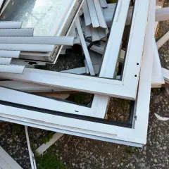 Stare okna PCV czekają na recykling. Widok pokazuje stos białych ram okiennych i szyb, gotowych do przetworzenia.