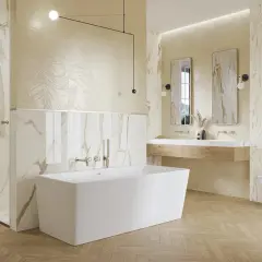 Elegancka łazienka z wanną wolnostojącą, prysznicem i podwójną umywalką. Dominują płytki imitujące marmur z subtelnymi złotymi żyłkami.
