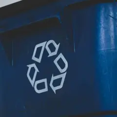 Niebieski śmietnik z symbolem recyklingu. Zastanawiasz się, jak mierzyć odległość śmietnika od okien, by zapewnić komfort i estetykę?