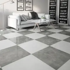 Nowoczesny salon z sofą i stolikiem kawowym, a na podłodze efektowna, szachownica z płytek w odcieniach szarości.