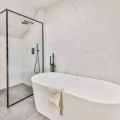 Nowoczesna łazienka z wanną wolnostojącą i prysznicem. Na podłodze elegancka płytka podłogowa 60x60 w odcieniu szarości.