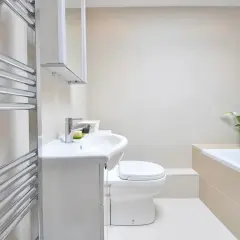 Beżowa łazienka inspiracje: nowoczesna armatura, biała ceramika i chromowany grzejnik tworzą elegancką przestrzeń.