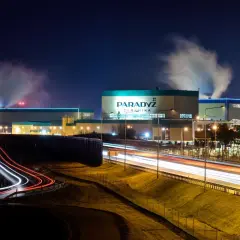 Nocą widać dymiący paradyż zakład produkcyjny w Tomaszowie Mazowieckim. Światła samochodów tworzą smugi na drodze.