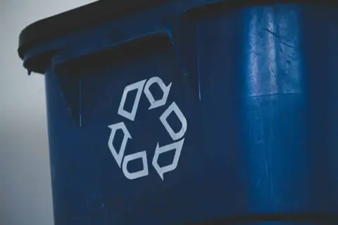 Niebieski śmietnik z symbolem recyklingu. Zastanawiasz się, jak mierzyć odległość śmietnika od okien, by zapewnić komfort i estetykę?