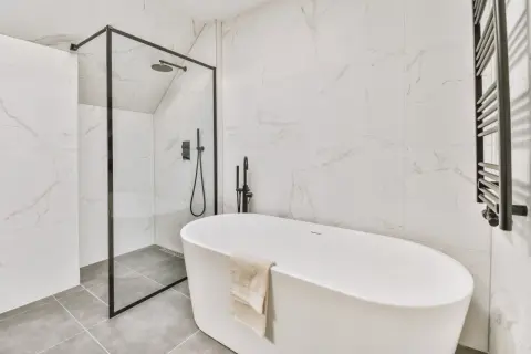 Nowoczesna łazienka z wanną wolnostojącą i prysznicem. Na podłodze elegancka płytka podłogowa 60x60 w odcieniu szarości.