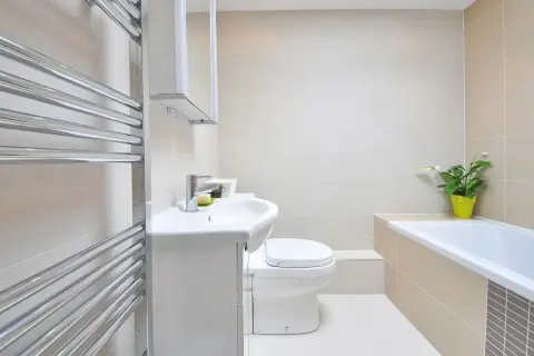 Beżowa łazienka inspiracje: nowoczesna armatura, biała ceramika i chromowany grzejnik tworzą elegancką przestrzeń.