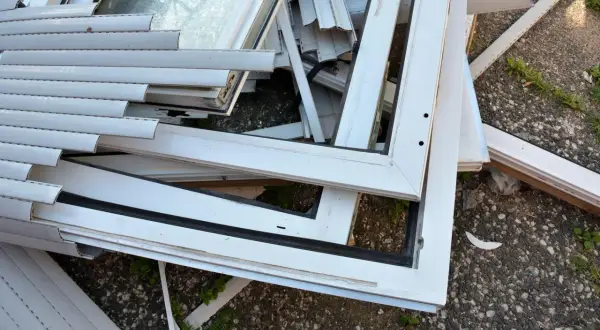 Stare okna PCV czekają na recykling. Widok pokazuje stos białych ram okiennych i szyb, gotowych do przetworzenia.