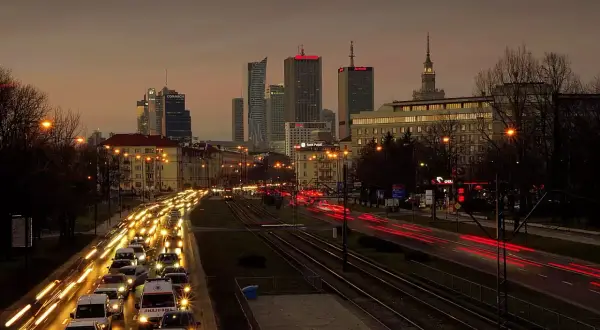 Warszawski krajobraz miejski o zmierzchu z korkiem ulicznym i światłami budynków.