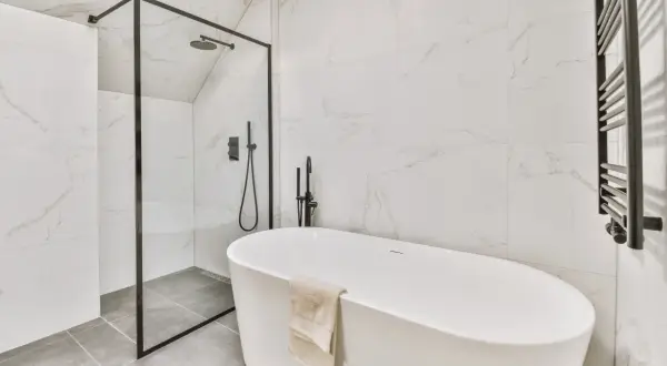 Nowoczesna łazienka z wanną wolnostojącą i prysznicem. Na podłodze elegancka płytka podłogowa 60x60 w odcieniu szarości.