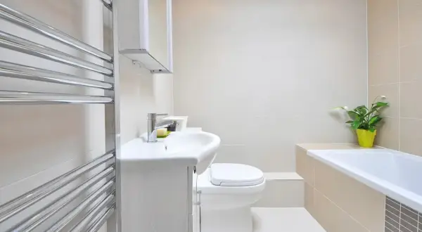 Beżowa łazienka inspiracje: nowoczesna armatura, biała ceramika i chromowany grzejnik tworzą elegancką przestrzeń.