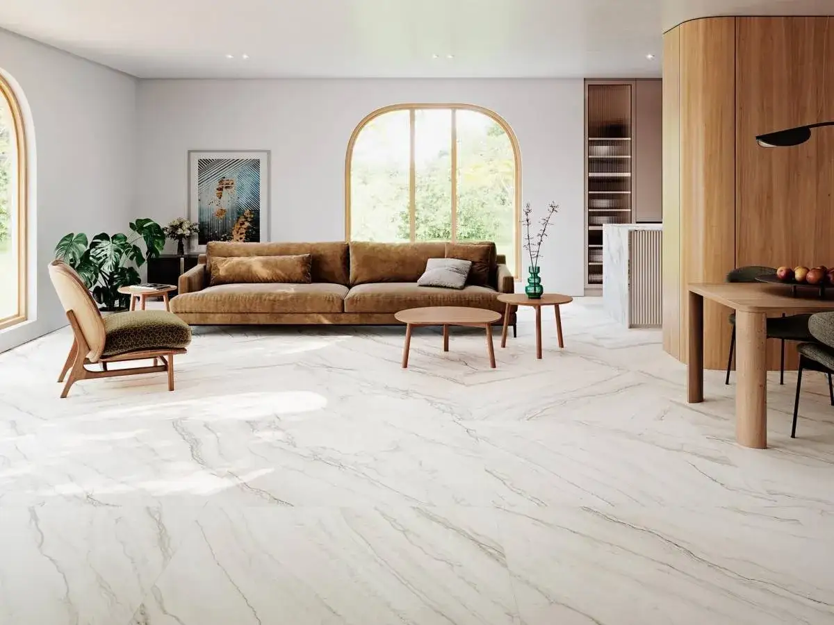Jasne, przestronne wnętrze z wygodną kanapą i designerskimi meblami, a na podłodze eleganckie płytki podłogowe 120x120 imitujące marmur.