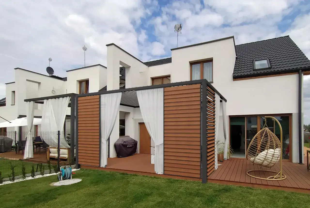 Nowoczesna pergola nad tarasem z drewnianymi panelami i białymi zasłonami. Idealne rozwiązanie, jak zrobić pergolę nad tarasem, by stworzyć przytulne miejsce.