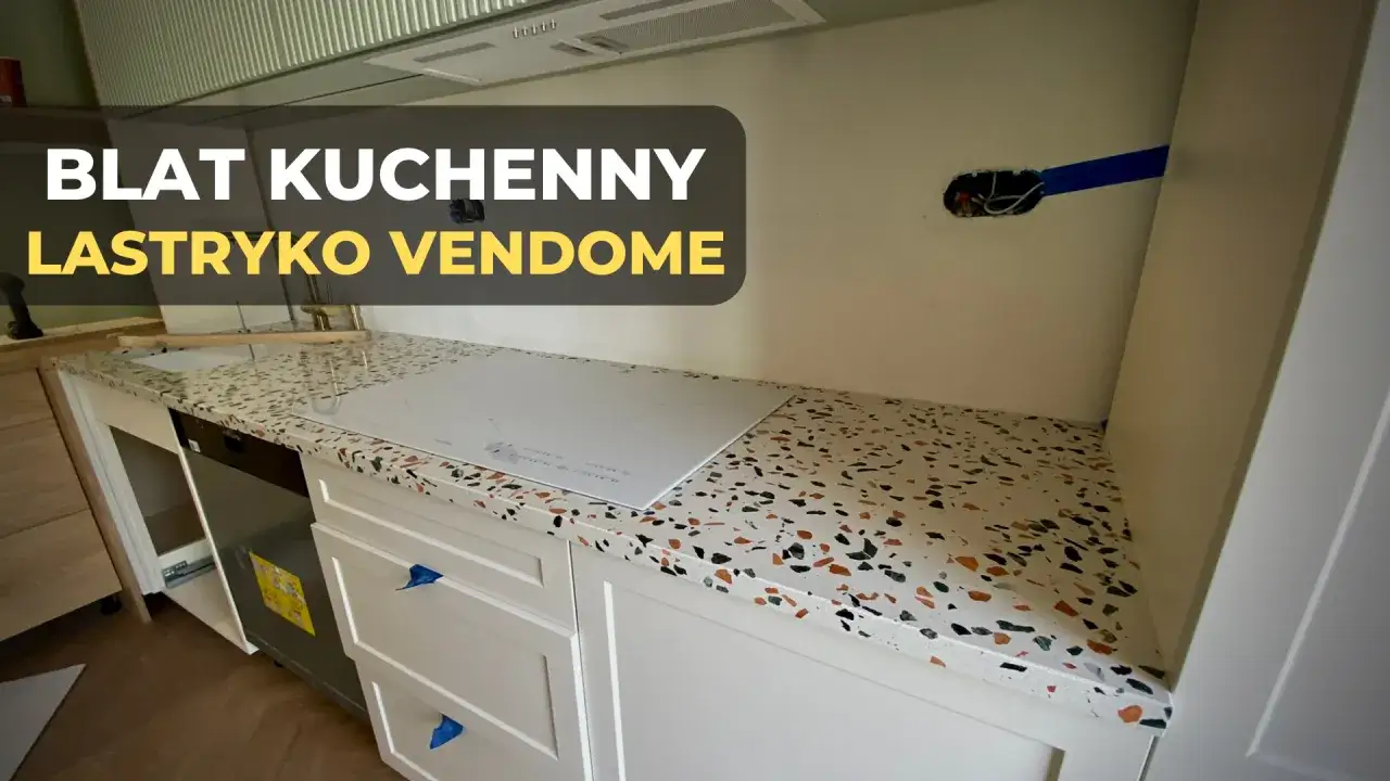 Nowoczesny blat kuchenny z lastryko Vendome, z płytą indukcyjną i białymi frontami szafek.
