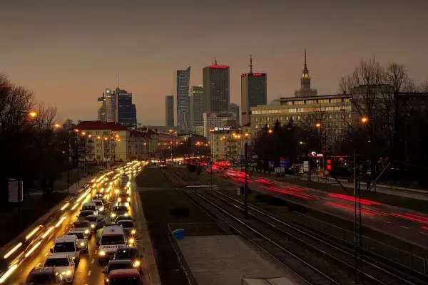 Warszawski krajobraz miejski o zmierzchu z korkiem ulicznym i światłami budynków.