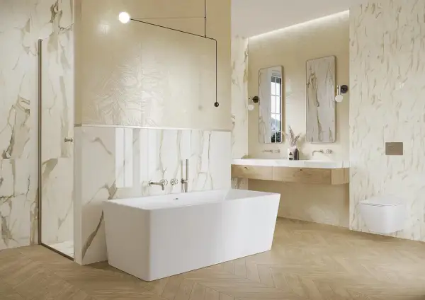 Elegancka łazienka z wanną wolnostojącą, prysznicem i podwójną umywalką. Dominują płytki imitujące marmur z subtelnymi złotymi żyłkami.