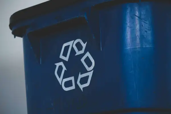 Niebieski śmietnik z symbolem recyklingu. Zastanawiasz się, jak mierzyć odległość śmietnika od okien, by zapewnić komfort i estetykę?