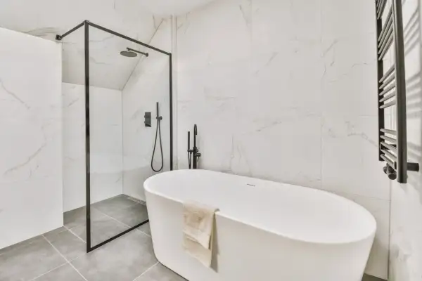 Nowoczesna łazienka z wanną wolnostojącą i prysznicem. Na podłodze elegancka płytka podłogowa 60x60 w odcieniu szarości.