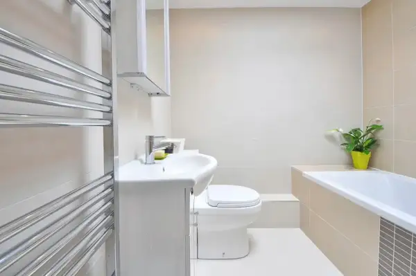 Beżowa łazienka inspiracje: nowoczesna armatura, biała ceramika i chromowany grzejnik tworzą elegancką przestrzeń.